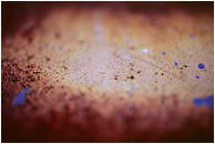 Rusted Steel, Paint Drops: Calgary, AB, Canada (2007) - Abstract photograph of blue paint splatter seeming to hover above a blurry, rusted steel plate