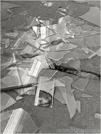 Fine art B&W photo showing a magazine clipping in a pile of shattered window glass