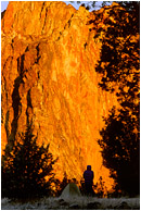 Terri, Tent, Orange Rock Sunrise: Smith Rocks, OR, USA (2002) - Lifestyle photo of a silhouetted woman and her tent, in front of a wall of bright orange, sunlit rock