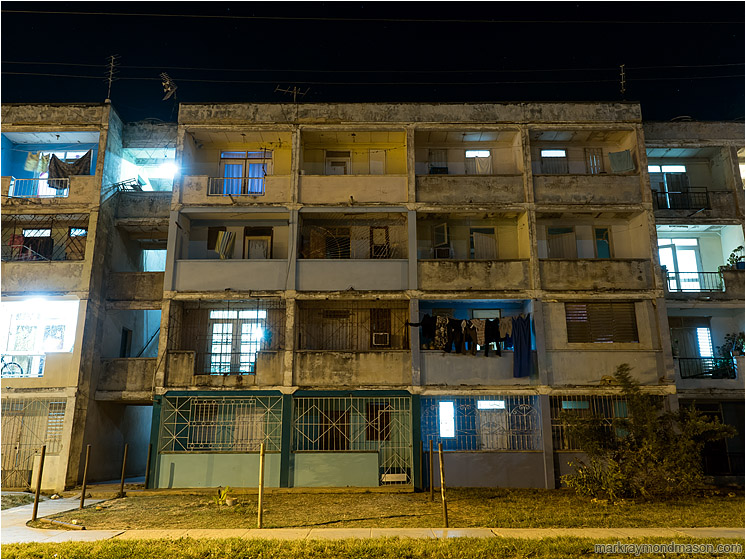 Apartment Block, Pale Lights: Santa Marta, Cuba (2017-02-12) - Fine art photograph showing lights in the windows of a very old and run-down apartment complex