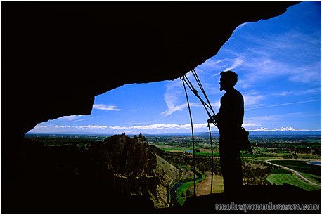 Lifestyle photograph showing a silhouetted climber standing under an overhanging cliff