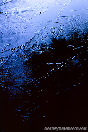 Abstract nature photograph of dark patterns in the ice of a frozen lake