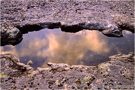 Fine art photograph of reflections in a pool of water, surrounded by textured rock