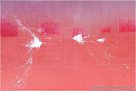 Abstract fine art photograph of arcs of white paint splashed over a dirty pink brick wall