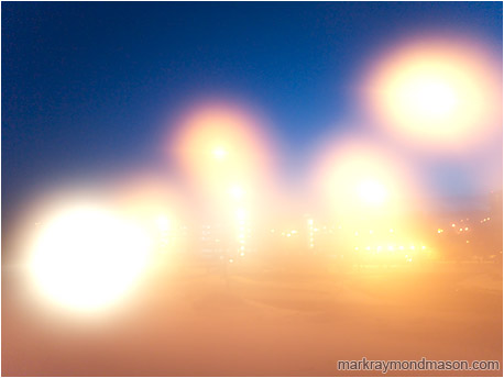 Abstract photograph of street lamps and lens flare against a dark night sky