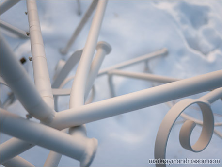 Abstract photograph of twisted white metal shapes against a frozen snowy field
