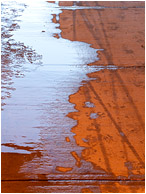 Meltwater, Concrete: Calgary, AB, Canada (2010) - Abstract photo of a red concrete walkway covered in ice, water and tire tracks