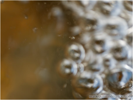 Abstract photograph showing blurred bubbles on one side of the frame and a muted pastel background on the other