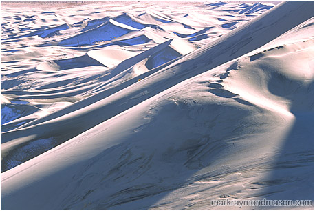 Abstract photograph of huge sand dunes, snow, and shadows deep in the desert