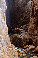 River Canyon, Mist: Near El Chorro, Spain (2006) - Fine art nature photograph of water and mist in a deep slot canyon, with steep cliffs of orange and black rock
