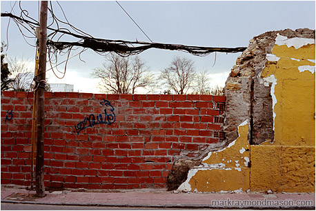 Fine art photograph of tangled wires, broken bricks, graffiti, and chipped plaster