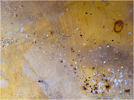 Abstract photograph showing paint flecks, sweeping patterns, and colourful stains in a aging, well-worn concrete floor