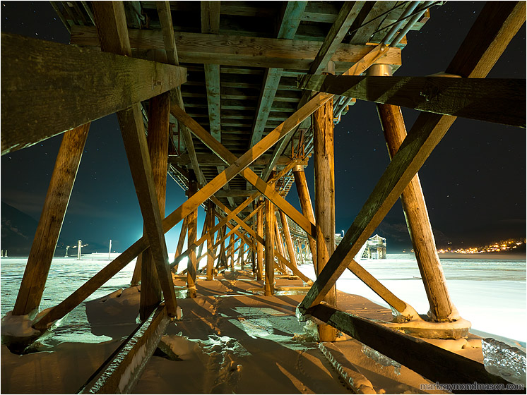 Beams, Ice, Night Sky: Salmon Arm, BC, Canada (2016-12-30) - Fine art photograph showing giant beams on the underside of a wharf, frozen in ice, set against a night sky with faint stars