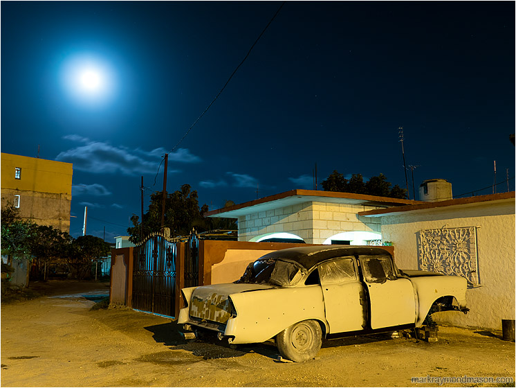 Broken Car, Moon, Night Sky: Santa Marta, Cuba (2017-02-12) - Fine art photograph showing an ancient car propped on blocks in the night with a hazy full moon in the background