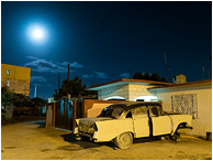 Broken Car, Moon, Night Sky: Santa Marta, Cuba (2017) - Fine art photograph showing an ancient car propped on blocks in the night with a hazy full moon in the background