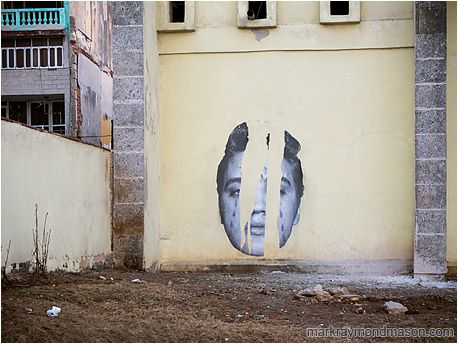 Fine art photo showing a torn street mural of Elvis in a rare unused space in downtown Havana