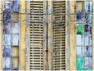 Glass, Slats, Bars: Regla, Cuba (2017) - Abstract photography showing small stained glass windows and wooden shutters behind ancient wrought-iron bars
