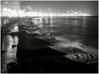 Worn Seawall, Night Skyline: Havana, Cuba (2017) - Fine art black and white night photograph of waves crashing against worn concrete water barriers