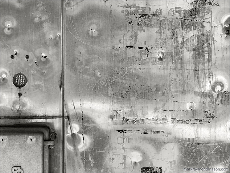 Dented Metal, Hinges: Salmon Arm, BC, Canada (2018-01-15) - Fine art abstract black and white photo showing a closeup of a dented metal train kiosk, reflected light forming patterns in the surface