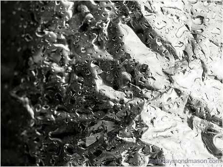 Abstract black and white photo of water beading on the crumpled remains of a foil weather balloon